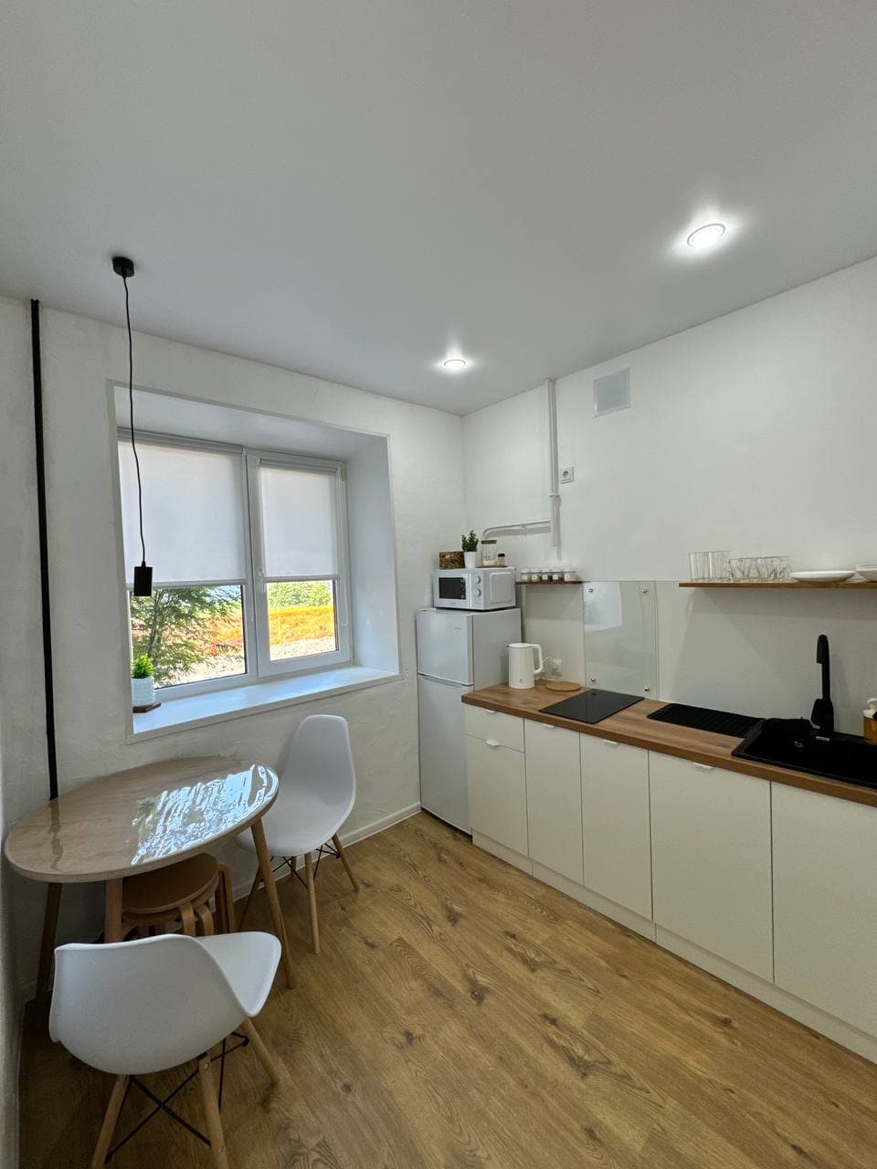 Светлая кухня с обеденным столом, холодильником и встроенной техникой